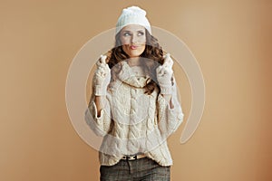 excited trendy woman in beige sweater, mittens and hat