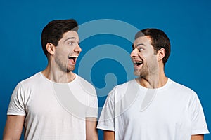 Excited unshaven two guys exclaiming while looking at each other