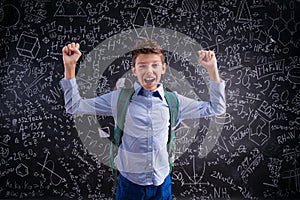 Excited and victorious boy against blackboard with mathematical