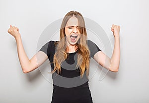 Excited winner casual woman loud shouting with opened mouth. Happy young teen girl on blue background