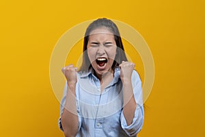 Excited winner woman scream after received good news isolated on yellow background.