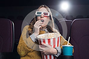 excited woman in 3d glasses eating popcorn and watching movie