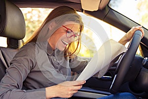 Excited woman in car reading papers
