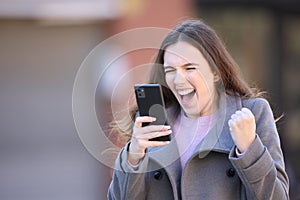 Excited woman celebrating good news holding phone