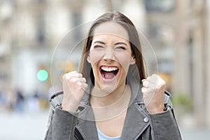 Excited woman celebrating good news in the street