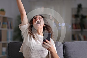 Excited woman celebrating success holding mobile phone