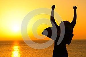 Excited woman celebrating success at sunrise