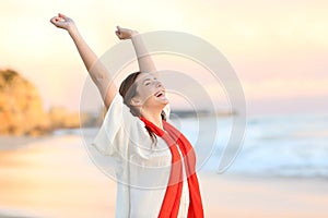 Excited woman celebrating sunset raising arms