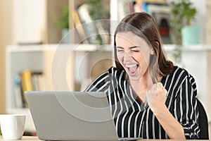 Excited woman checking good news on laptop