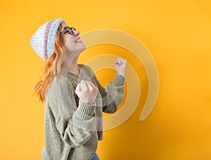 Excited woman with clenched fists and teeth, isolated on yellow background. Yes concept. Good news. Rejoicing female celebrates