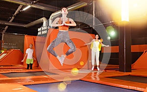 Excited woman enjoying jumping at well-equipped indoor trampoline arena