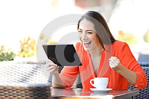 Excited woman finding online offers on tablet in a bar