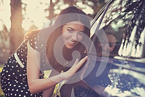 Excited woman and her new car with sunlit forest in background