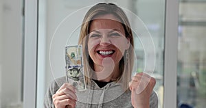 Excited woman holding cash dollar bills in hands