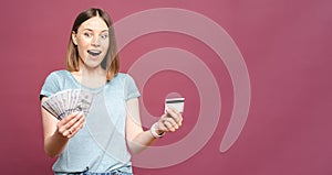 Excited woman holding money and credit card isolated over pink crimson background