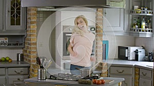 Excited woman in kitchen doing a silly dance and preparing food