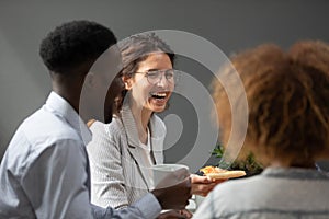 Excited woman laughing at funny joke, eating pizza with colleagues