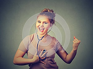 Excited woman listening to her heart with stethoscope