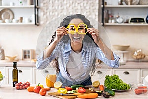 Excited woman making glasses of sweet pepper, having fun and playing with food while cooking fresh salad