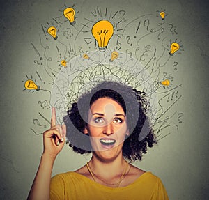 Excited woman with many ideas light bulbs above head looking up