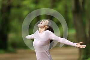 Excited woman outstretching arms in a forest celebrating