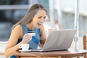 Excited woman paying on line with a credit card