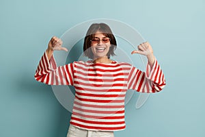 Excited woman pointing at herself in studio