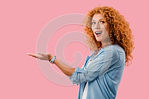 Excited woman presenting something isolated on pink