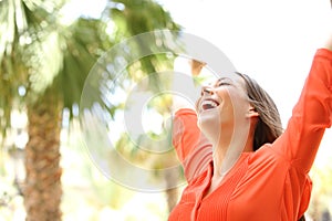 Excited woman raising arms outdoors