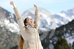 Excited woman raising arms in the snowy mountain