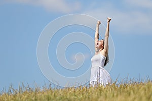 Excited woman raising arms in a wheat field