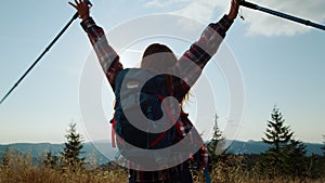 Excited woman raising hands during hike in mountains. Hiker feeling freedom