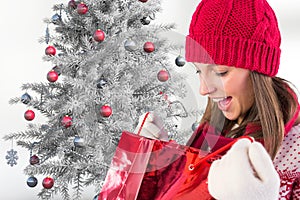 Excited woman in red beanie cap checking her christmas gifts