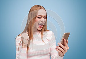 Excited woman screaming while checking smartphone