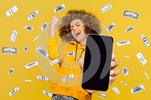 Excited woman showing big empty screen for promotional text or advertisement, standing in money rain