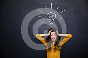 Excited woman with tousled hair standing over blackboard background