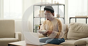 Excited woman using laptop and celebrating success holding a bundle of cash dollars