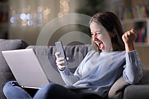 Excited woman using phone and laptop in the night photo