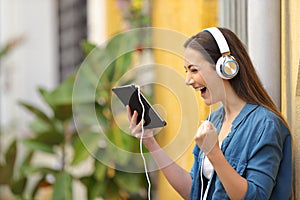Excited woman wearing headphones watching tablet content