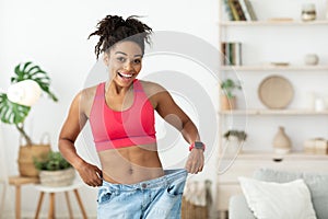 Excited Woman Wearing Too Big Jeans After Weight Loss Indoor