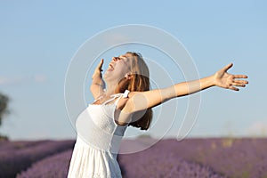 Excited woman in white outstretching arms in lavender