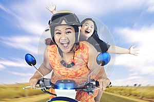 Excited women rides scooter on countryside road