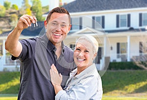 Excited Young Adult Couple With House Keys In Front of Beautiful Home