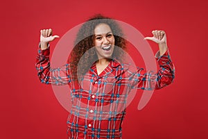 Excited young african american girl in pajamas homewear posing resting at home isolated on red background in studio