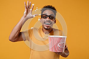 Excited young african american guy in 3d imax glasses posing isolated on yellow orange background. People lifestyle