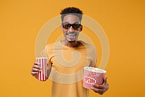 Excited young african american guy in 3d imax glasses posing isolated on yellow orange background. People lifestyle photo