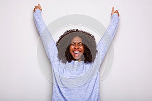 Excited young african american woman cheering with hands raised against white background