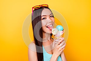 Excited young asian lady licks tasty ice cream of three scoops o