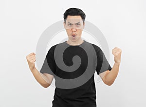 Excited young Asian man raising his fists with happy delighted face, celebrating success isolated on white background.