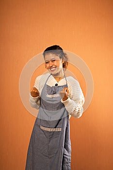 excited young Asian woman wearing apron with fisted hands